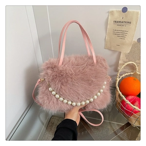 Dettaglio della borsa in peluche rosa con catena di perle e texture in finta pelliccia