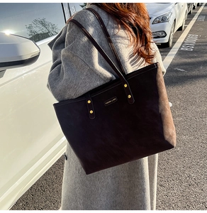 Detail of dark brown suede tote bag with metal plate worn with a grey wool coat