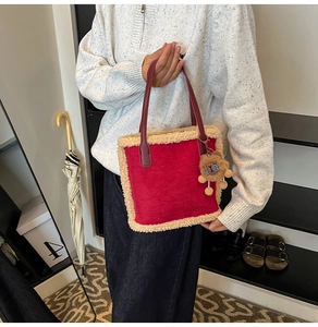 Détail d'un sac à main rouge en peluche avec bordure en fausse fourrure et breloque lion