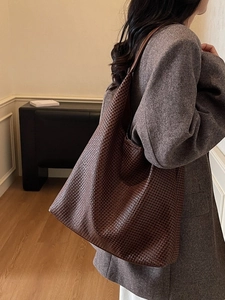 Deep brown oversized woven leather tote bag shown in a stylish minimalist interior setting