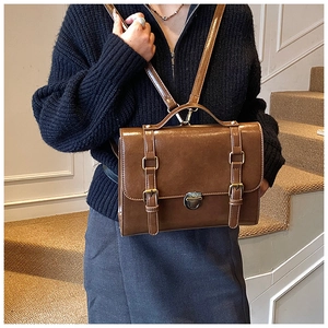 Detail of vintage brown messenger bag with metal turn-lock and buckle closure on stairs