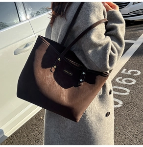 Detail view of large dark brown suede tote bag carried on shoulder for autumn winter style