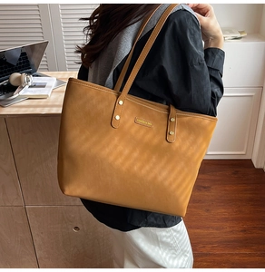 Detail view of the brown leather tote bag texture with elegant gold stud accents