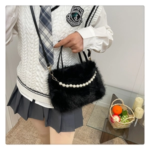 Dettaglio della borsa in peluche nera con perle bianche e chiusura in metallo dorato