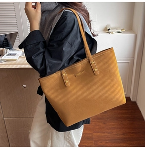 Detail of vintage brown tote bag showing smooth PU leather texture and gold metal rivet accents