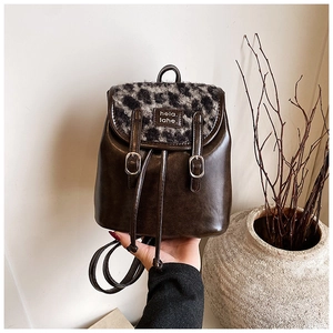 Dettaglio di uno zaino vintage in pelle con patta leopardata ed etichetta tessuta di marca