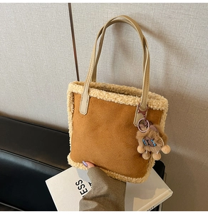 Détail d'un sac cabas en daim marron avec bordure en fausse fourrure crème et breloque