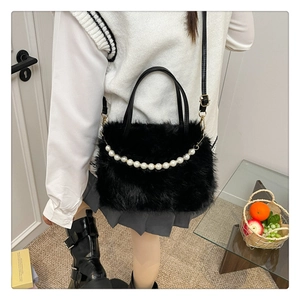 Dettaglio borsa in ecopelliccia nera con elegante catena di perle e tracolla in pelle