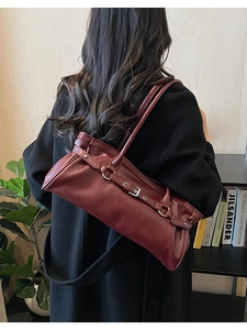 Détail du sac baguette en cuir bordeaux avec boucle métallique et fines bandoulières