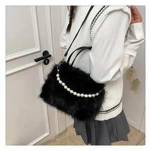 Vista laterale della borsa in peluche nero con catena di perle su una modella