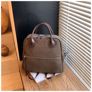 Détail du sac à dos rétro en daim marron avec poignées en cuir sur surface en bois