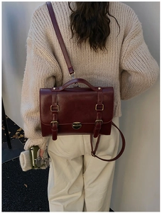 Retro burgundy satchel with vintage metal buckles styled with a cozy winter sweater