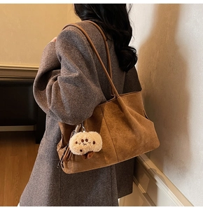 Brown suede tote bag with mushroom charm shown from a side-view on model shoulder