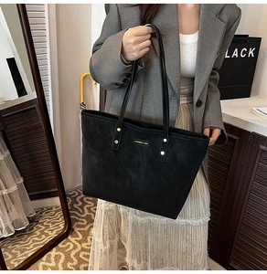Detail of black matte tote bag with thin leather straps and metal fashion logo lettering
