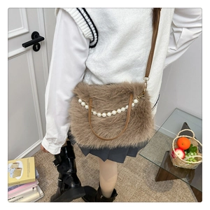 Borsa a spalla in peluche marrone con manico di perle indossata da modella in interni