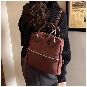 Sac à dos en daim marron avec fermetures éclair argentées porté par un mannequin