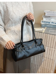 Gros plan du sac baguette en simili cuir noir avec boucles argentées et sangles