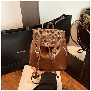 Dettaglio mini zaino con patta a motivo leopardato e trama in pelle marrone scuro opaca