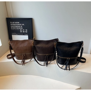 Détail de sacs seaux vintage en cuir marron et noir avec décorations à franges