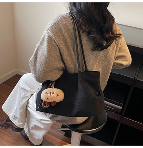 Chic black matte oversized tote bag with plush paw charm shown on model's shoulder