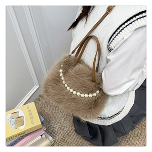 Dettaglio della borsa in peluche marrone con manico di perle e tracolla in pelle