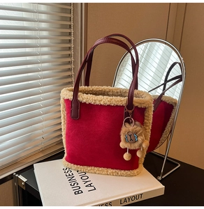 Détail d'un sac cabas en daim rouge avec bordure en fausse fourrure beige et grigri