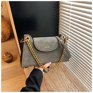 Vue détaillée du sac à bandoulière en cuir mat gris avec chaîne dorée et logo gravé
