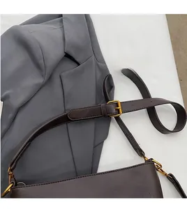 Détail de la bandoulière réglable en cuir marron foncé avec boucle métallique dorée