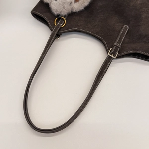 Detailed view of dark brown suede tote bag with contrast stitching and gold hardware