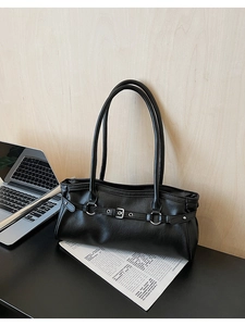 Détail d'un sac baguette noir vintage avec boucle argentée et décor de bureau urbain