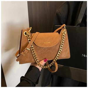 Détail du sac à main en daim marron caramel avec chaîne dorée et logo embossé