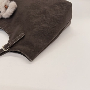 Close-up of vintage dark brown tote bag with contrast stitching and plush keychain