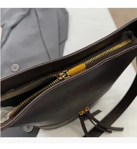 Gros plan détaillé de la fermeture éclair dorée et du gland en cuir sur le sac seau marron