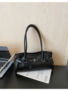 Détail d'un sac baguette noir en cuir avec anneau argenté sur un bureau de style moderne