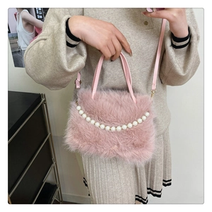 Borsa in ecopelliccia rosa con manico di perle e tracolla indossata da una modella
