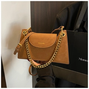 Détail du sac bandoulière en daim caramel avec chaîne dorée et logo embossé