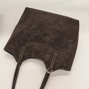 Macro detail of dark brown tote bag showing textured leather and white contrast stitching