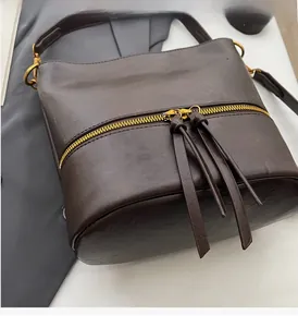 Gros plan détaillé sur la fermeture éclair dorée et les tirettes en cuir d'un sac marron