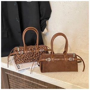 Detail view of retro leopard print and brown suede barrel bags with silver metal buckles