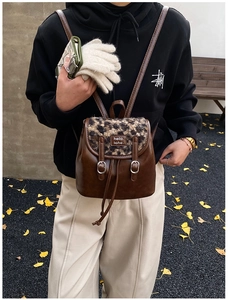 Dettaglio di uno zaino in pelle marrone con patta leopardata e fibbia in metallo