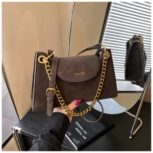 Détail d'un sac à bandoulière marron vintage avec chaîne dorée et rabat magnétique