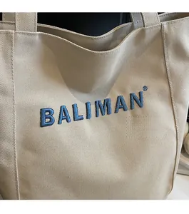 Close-up of high-density blue BALIMAN letter embroidery on a beige canvas tote bag
