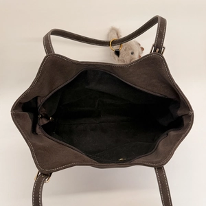 Top view of large coffee brown suede tote bag featuring white stitching and plush charm