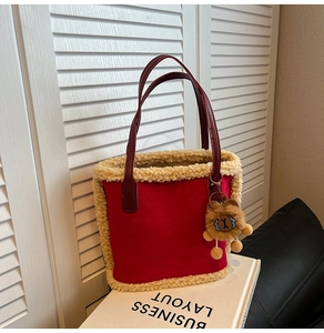 Détail du sac cabas rouge en peluche avec bordure polaire et porte-clé lion sur livre