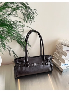 Détail du sac baguette en cuir marron foncé avec boucle métallique vintage et poignées