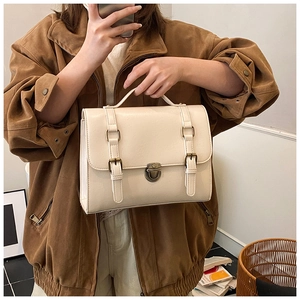 Detail shot of vintage cream satchel featuring metal buckle and textured faux leather finish