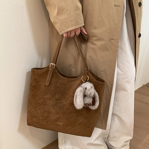 Detail of vintage dark brown tote bag with plush rabbit charm and gold logo branding