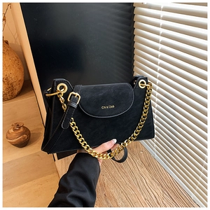 Détail du sac à rabat noir avec chaîne dorée et marquage sur la surface en cuir texturé