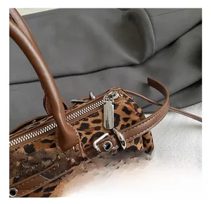 Detailed close-up of the leopard print bag showing silver hardware and brown leather strap