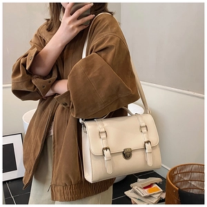 Detail of off-white vintage satchel featuring double bronze buckles and a flip-top cover
